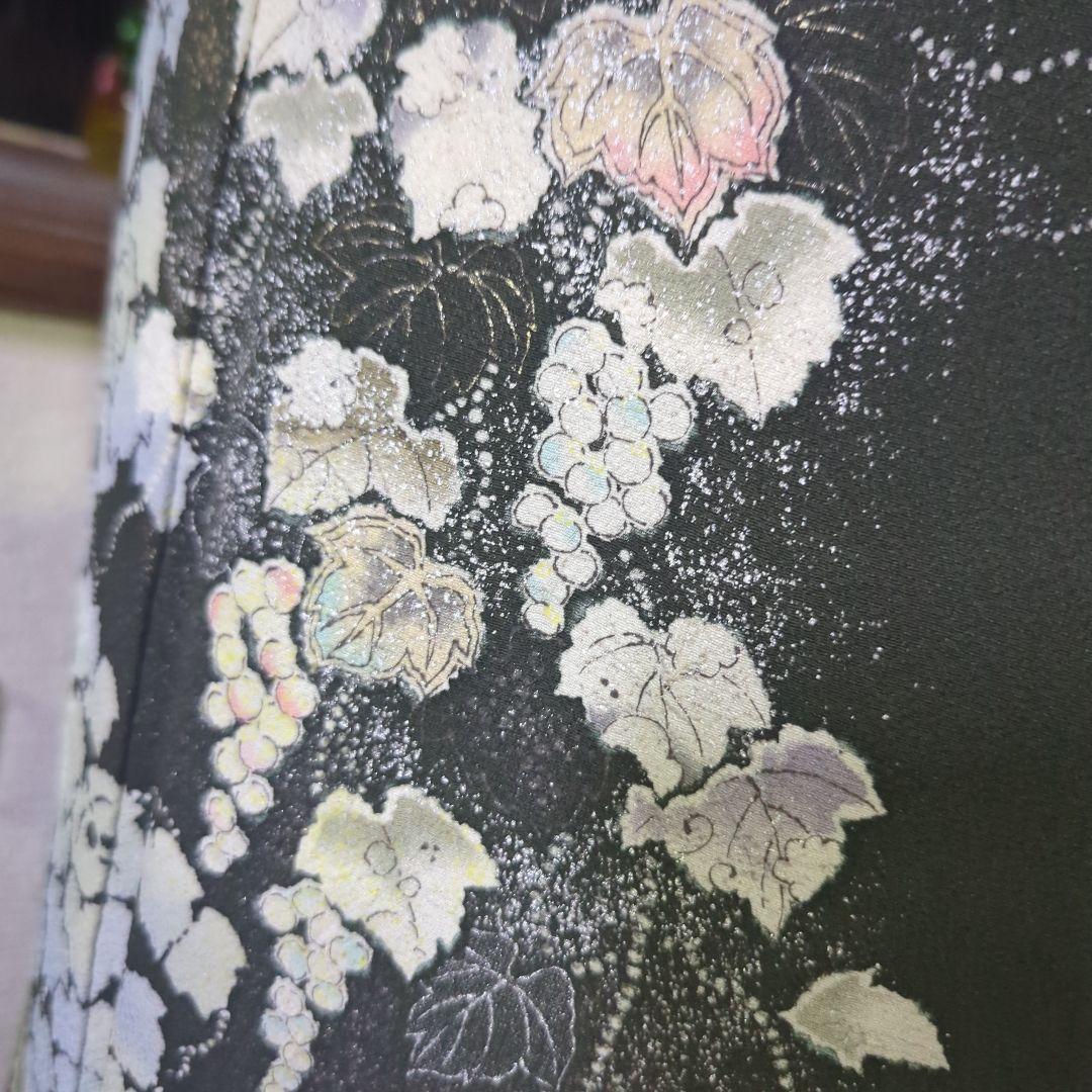 落款が入ります、青丹色の地に煌めく葡萄柄が繊細な美しさを見せる正絹訪問着です