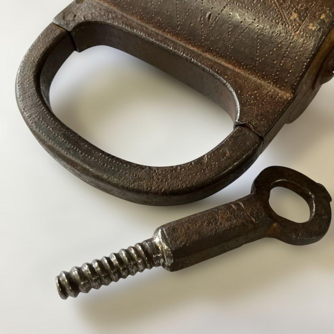 アンティークな鉄製スクリュー式円筒型南京錠（表面には点描幾何学模様）